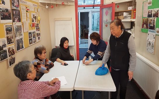 Lambeth Chinese Community association members gather around table for a meeting