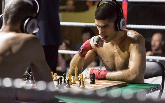 Two people playing chess with their shirts off.