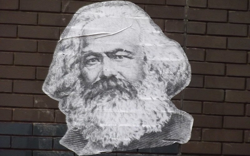 A poster of Karl Marx on a brick wall