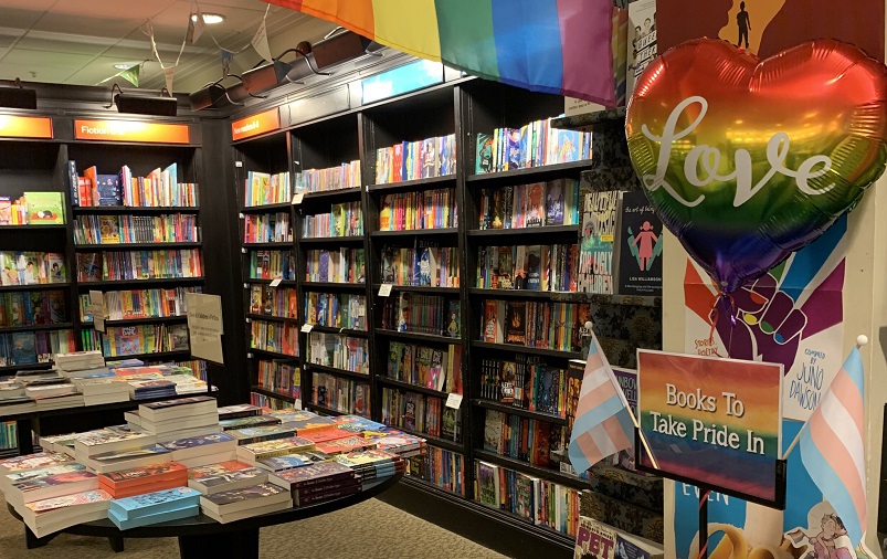 The inside of Croydon Waterstones. Shelves of books, and a display with gay and trans pride flags and a sign saying 'books to take pride in'.