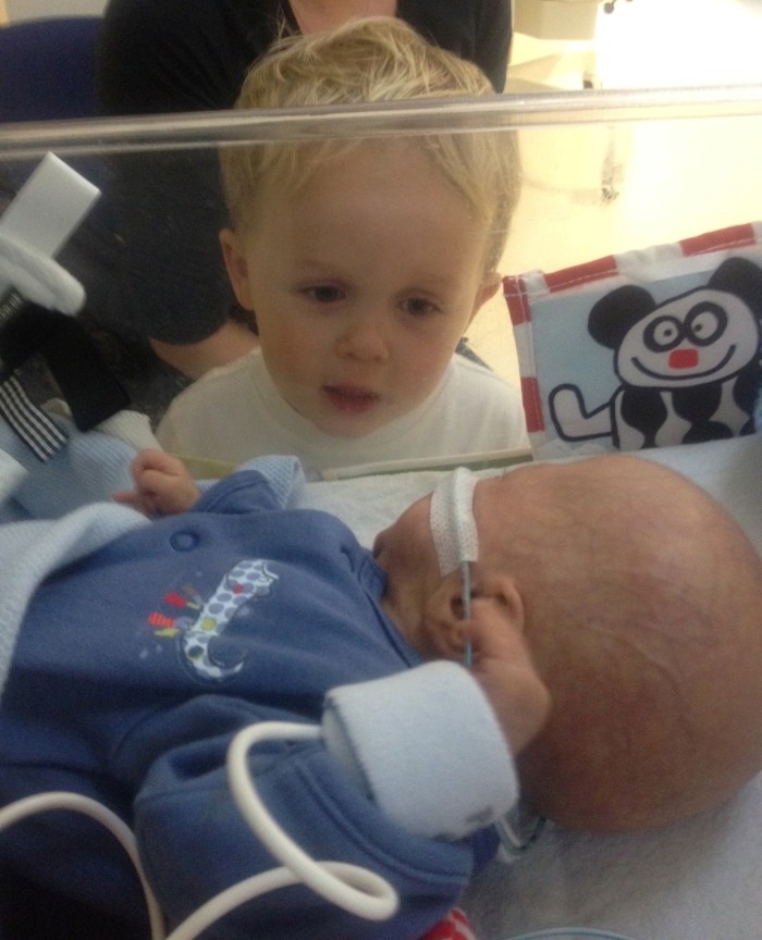 Ted looking at his brother through incubator