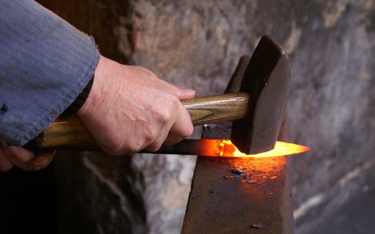 Blacksmith crafts knife using hammer