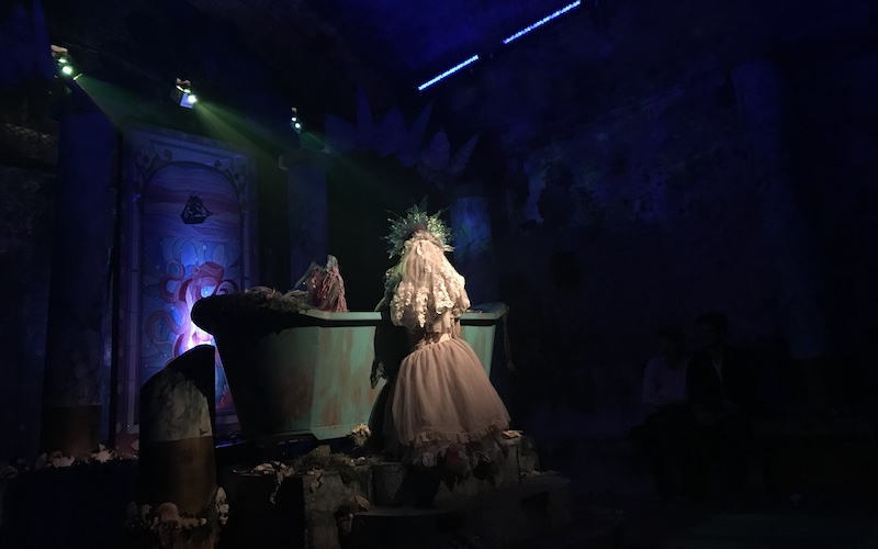 Performer kneeling at a bathtub at Red Palace
