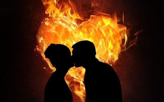 Shadow of couple kissing in front of burning heart