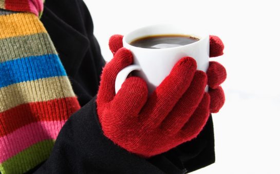 Hands in winter gloves holding mug of hot cocoa