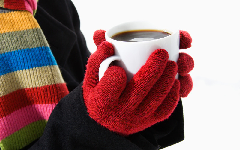 Hands in winter gloves holding mug of hot cocoa