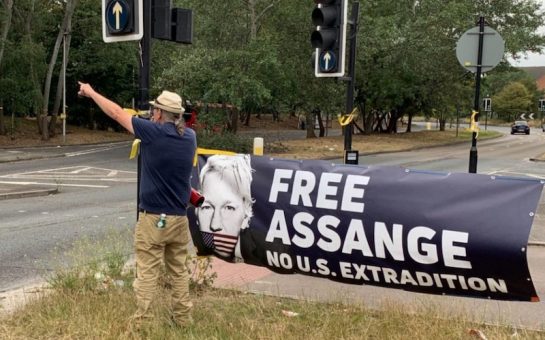 A protester talks into a megaphone in front of a banner saying Free Assange No US extradition
