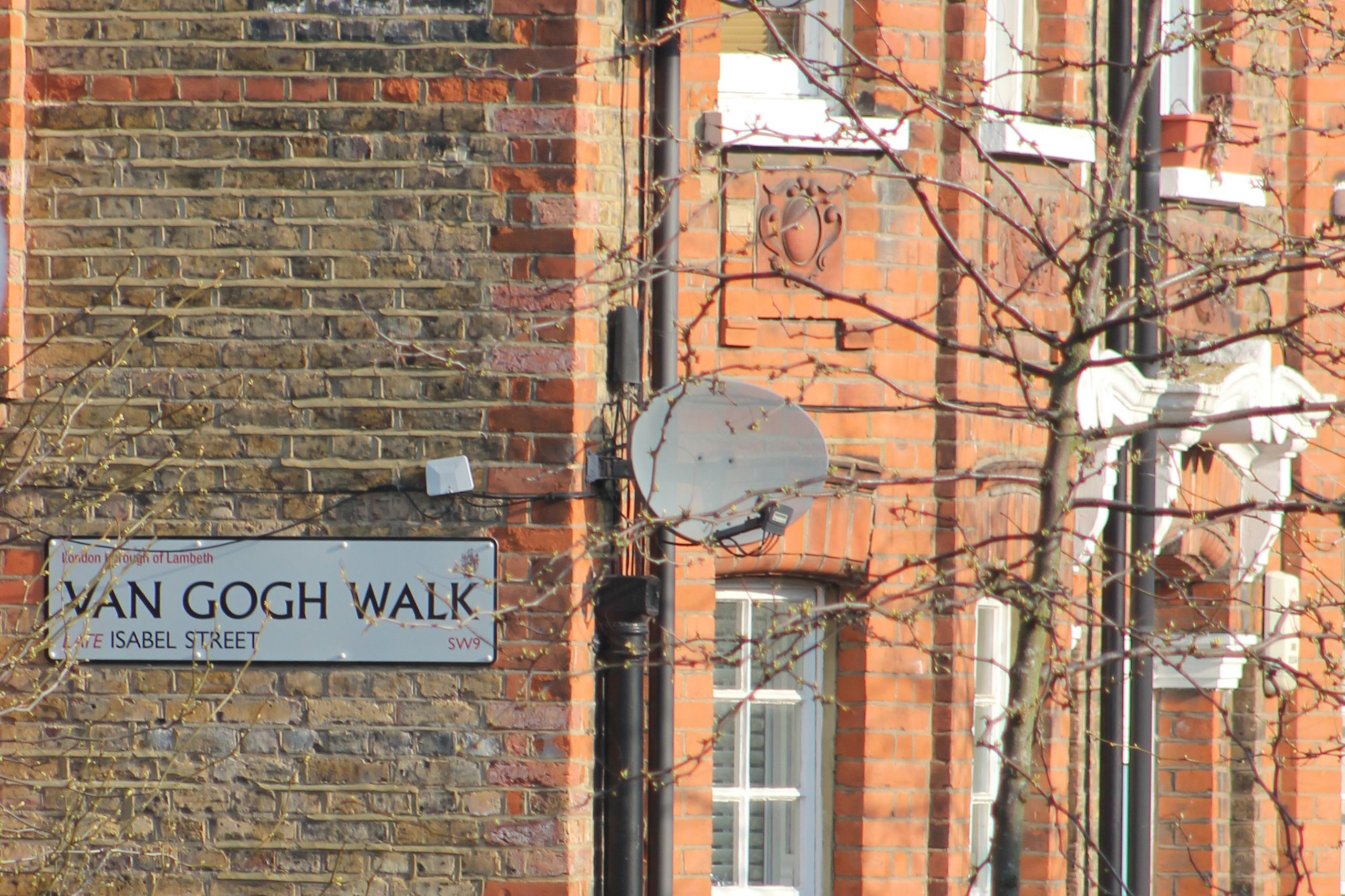 A street sign reads 'Van Gogh Walk' on a brick wall. 