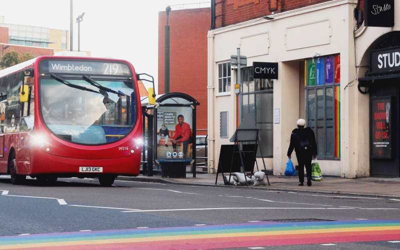 A bus to Wimbledon stopped outside of Bar CMYK and the LGBT+ rainbow crossing.