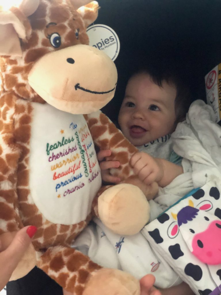 Teo receives a personalised giraffe from the charity Cranio Ribbons