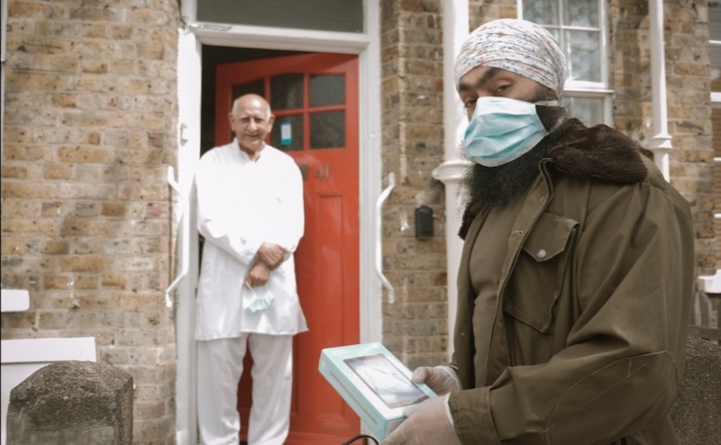 Ready Tech Go volunteer gives a device to an older resident