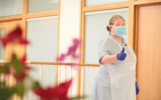 A nurse at Trinity Hospice gives a thumbs up in a mask