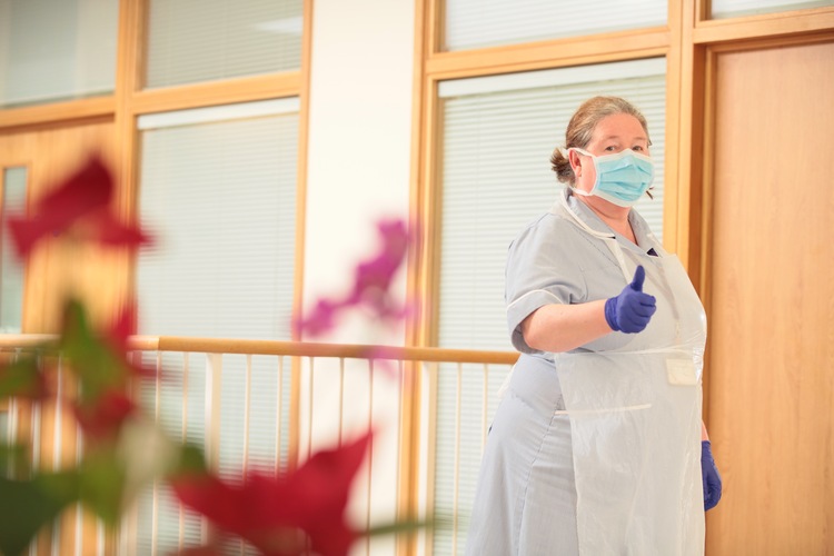A nurse at Trinity Hospice gives a thumbs up in a mask