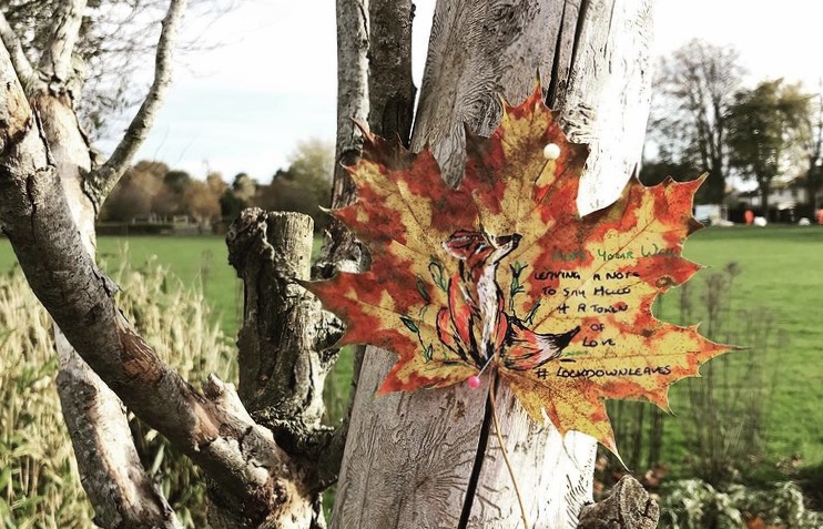A leaf pinned to a tree trunk with a brightly coloured fox drawn on it