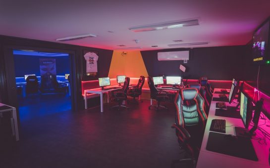 A photo of the Roehampton University Esports Arena. Several gaming PCs and chairs are around the room