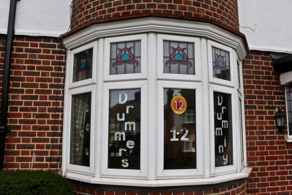 A bay window decorated with a number 12 and with teh words 12 drummers drumming in stickers on the window panes