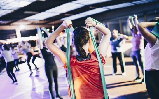 Women wearing read top doing an exercise class using green resistance bands
