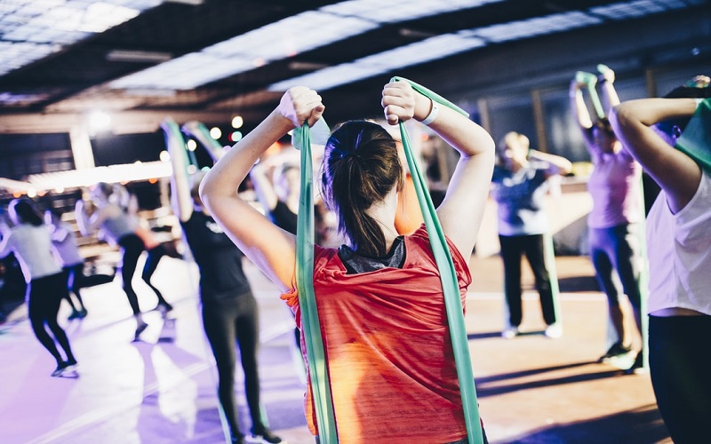 Women wearing read top doing an exercise class using green resistance bands