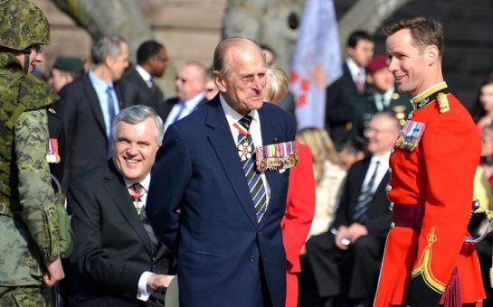 Prince Philip in a military uniform in the centre of the image smiling at another uniformed officer.