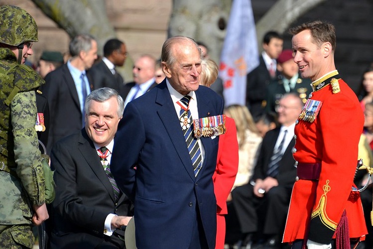 Prince Philip in a military uniform in the centre of the image smiling at another uniformed officer.