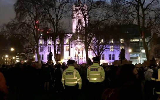 A large group of people at the #KillTheBill protest with two policemen in fluorescent yellow jackets in the foreground
