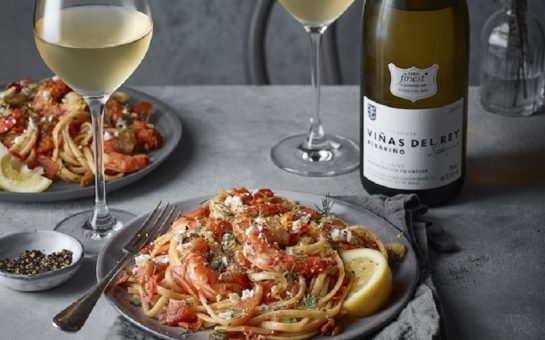 Two plates of spaghetti with two glasses of wine