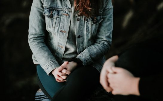 young woman sat with hands together on her lap