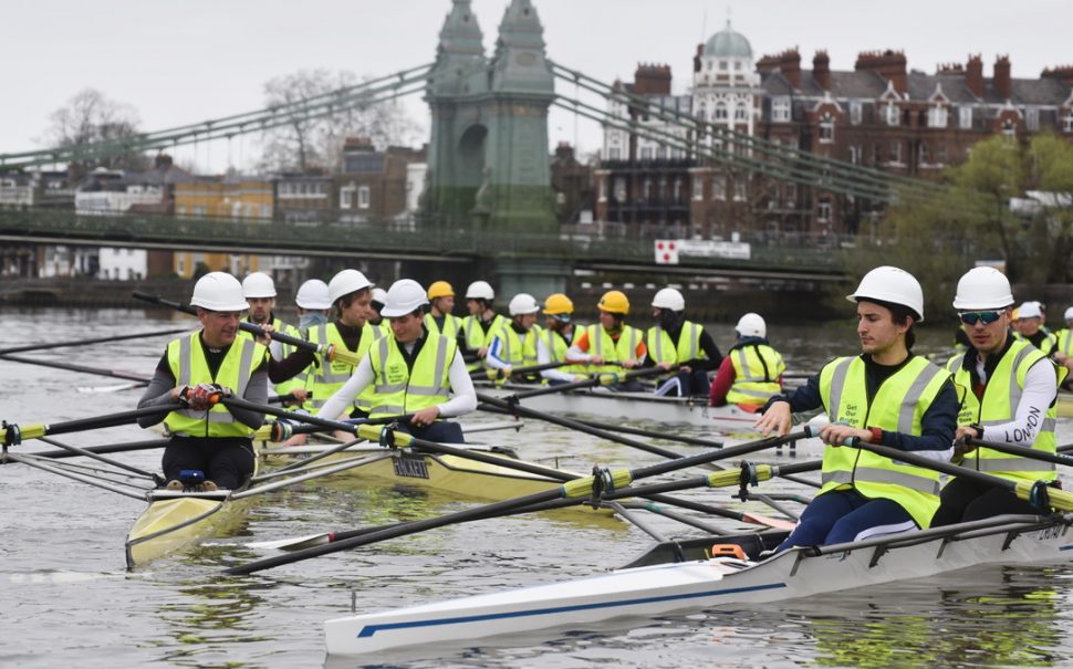 Rowers in hard hats and high-vis vests in front of closed Hammersmith Bridge
