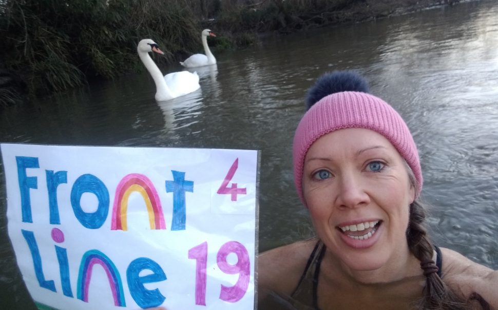 Susi Halley in the river Thames holding up Frontline19 sign