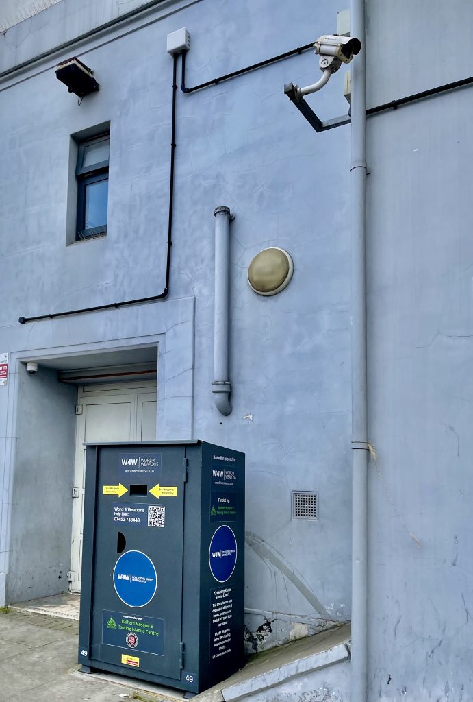 Picture of the knife bin placed outside of the Islamic Centre. The image conveys that a nearby security camera has been purposely moved so that the bin cannot be seen.