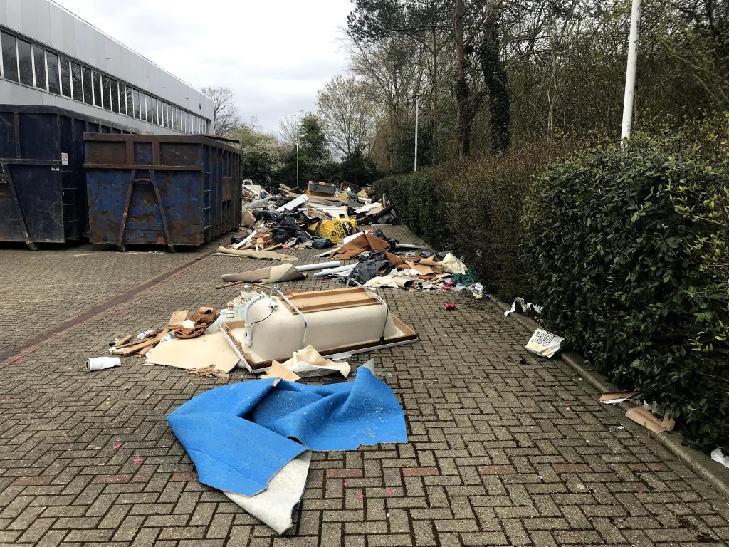 Bathtub and tons of other flytipped rubbish pictured next to industrial skips used for clearing.