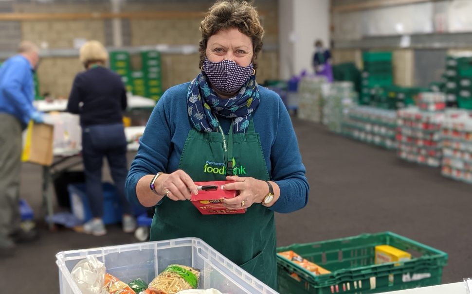 Woman in an apron and face mask distributing food parcels
