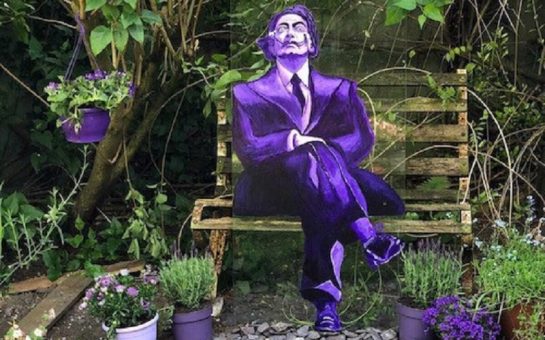 Salvador Dali painted on glass seated on a bench in the garden