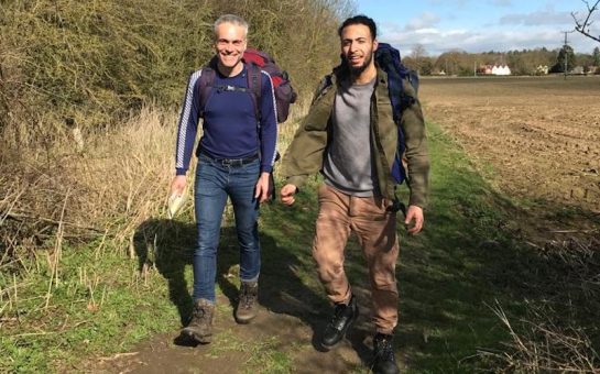 Yusuf and Jon on a hiking trip before lockdown. Both are smiling and have backpacks.