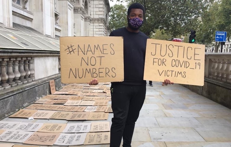 A campaigner holds plaques bearing the slogans #NamesNotNumbers and Justice for Covid-19 Victims