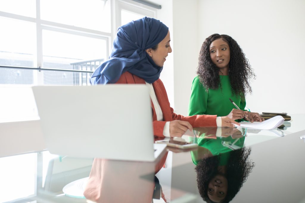 Woman in hijab and Black woman discussing money matters. diverse