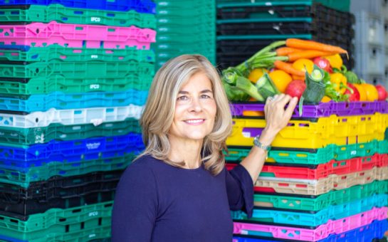 Laura Winningham stands in front of crates of vegetables stacked