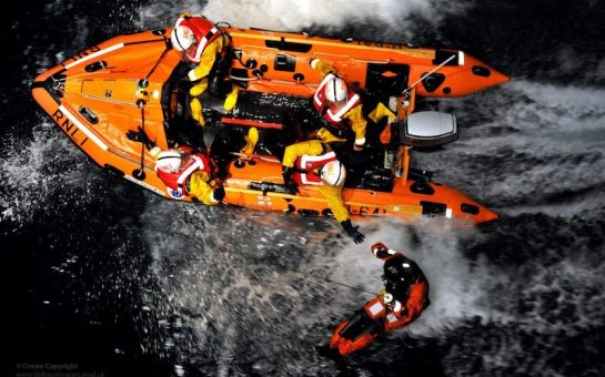 RNLI crew members carrying out a rescue. Shot from above.