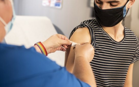 Young man receiving plaster on injection site post vaccination