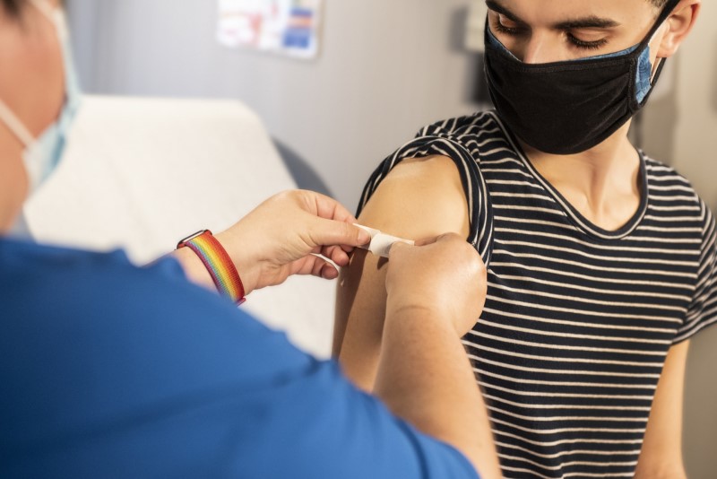 Young man receiving plaster on injection site post vaccination