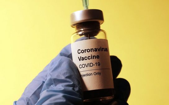 Bottle of a COVID vaccine on yellow background