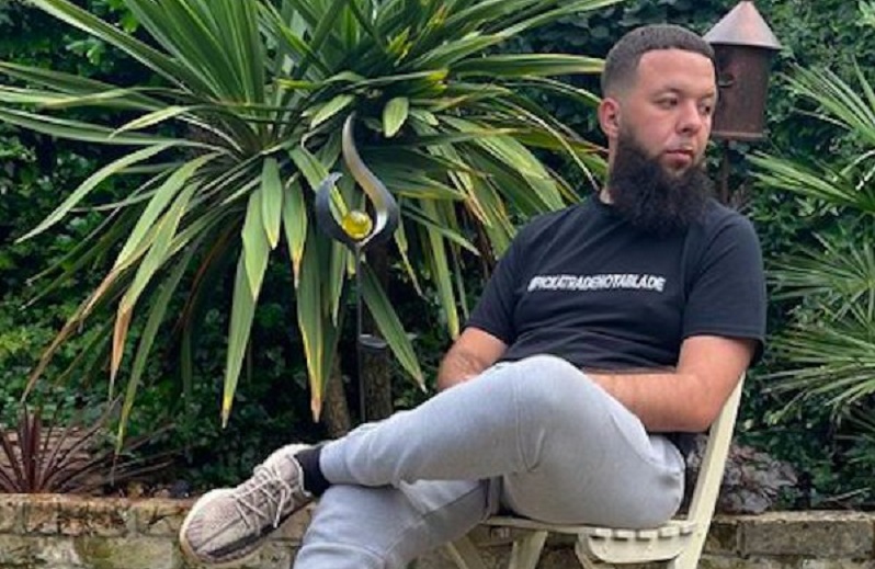 Hafid sitting in a chair in a garden with plants in the background