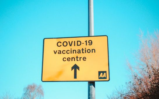 An image of a UK roadside sign pointing out the direction of a Covid-19 vaccination centre