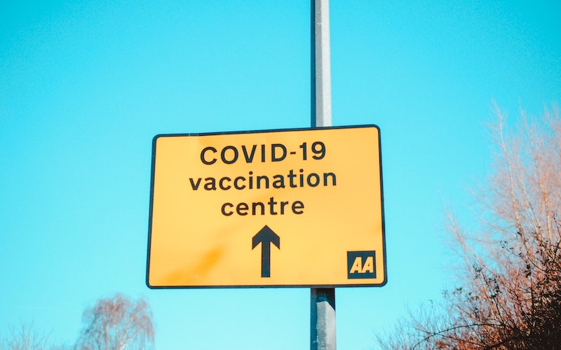 An image of a UK roadside sign pointing out the direction of a Covid-19 vaccination centre