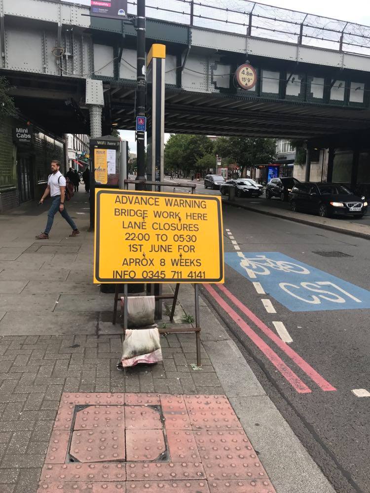Yellow sign in front of Balham Railway Bridge saying Advance Warning: Bridge work here. Lane closures. 22:00 to 05:30. 1st June for approx 8 weeks. Info 0345 711 4141."