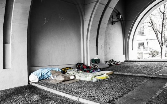 Sleeping bags and belongings under an archway from people sleeping rough