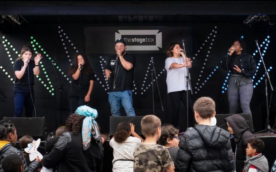 People standing on stage outside, beatboxing