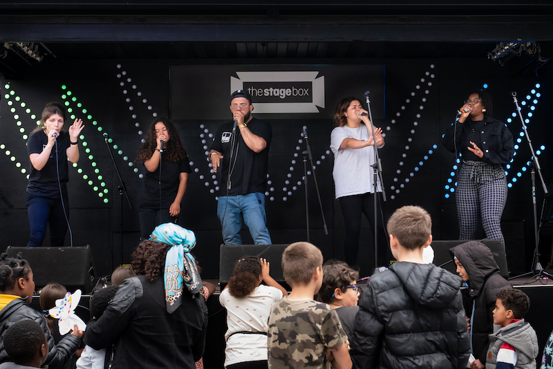 People standing on stage outside, beatboxing