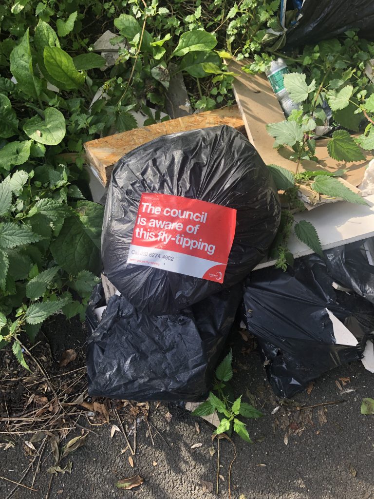 Bag of Rubbish with sign by the council saying they are "aware of this fly-tipping"