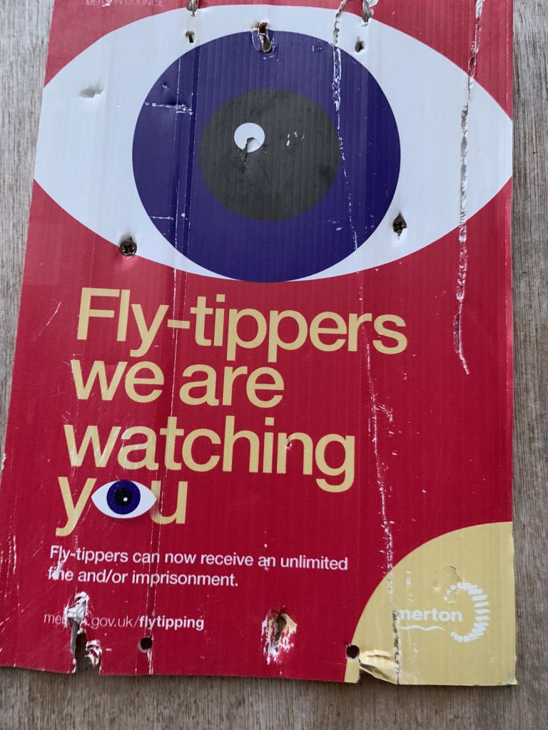 Poster with large eye on a red background with the warning "Fly-tippers we are watching you"